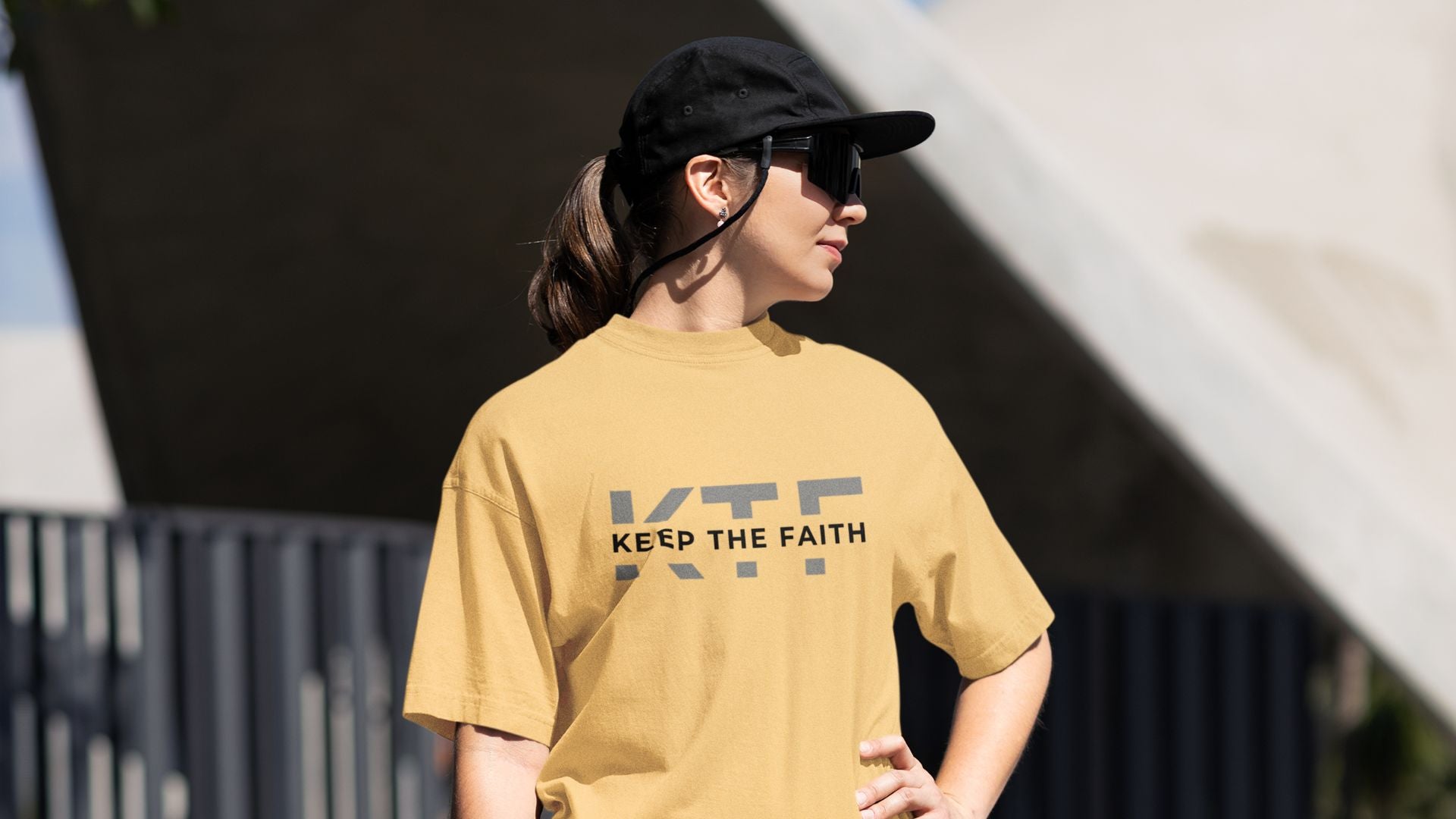 Woman in beige Keep The Faith t-shirt and black cap outdoors