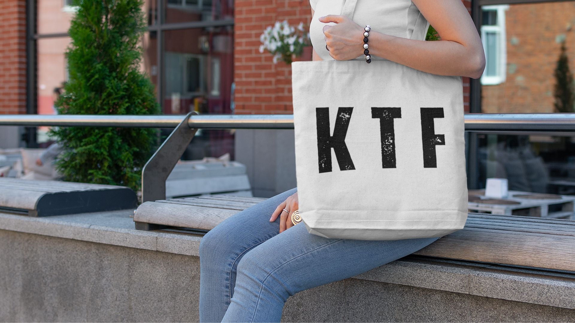 Woman carrying white KTF Keep The Faith tote bag outdoors