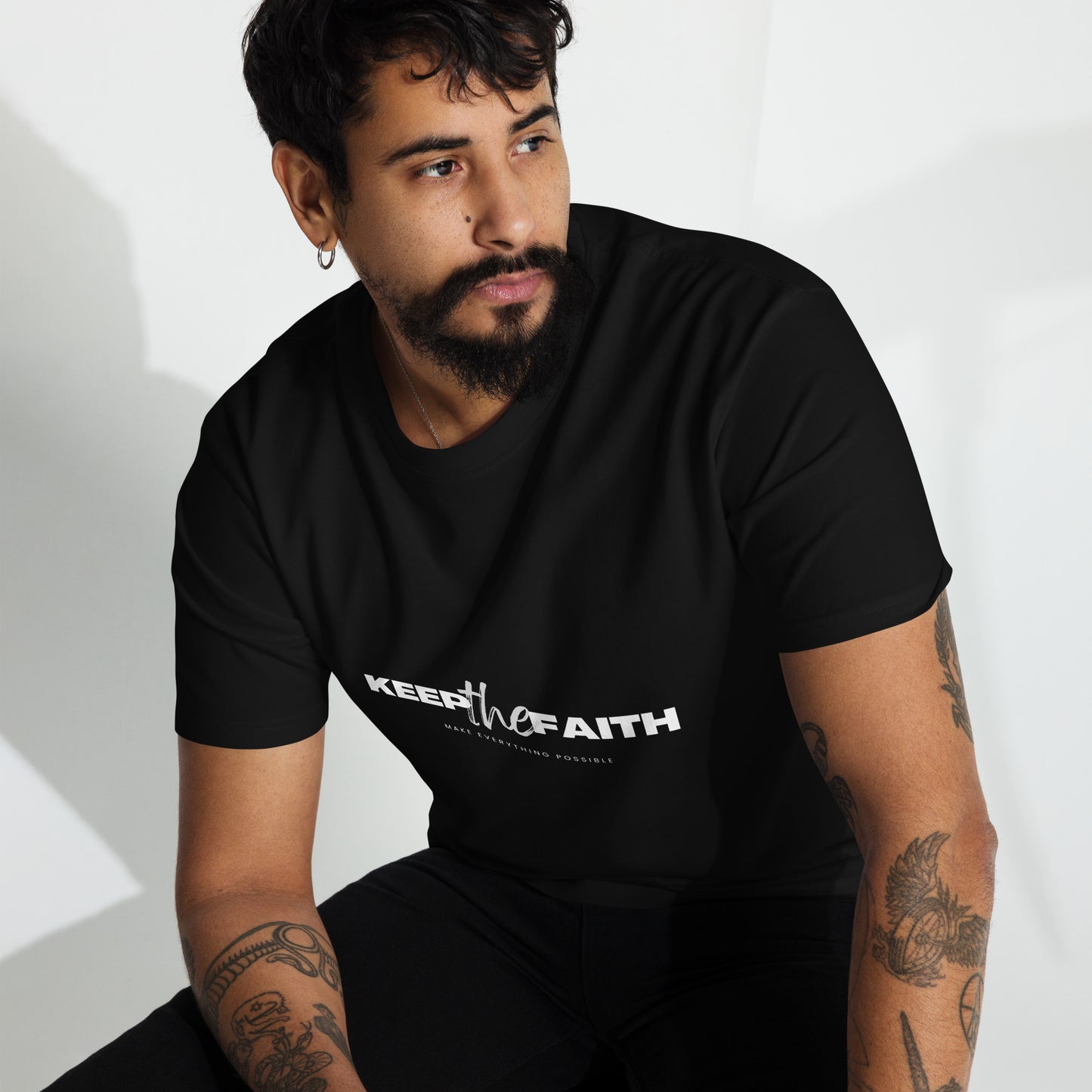 Man wearing black Keep The Faith t-shirt sitting indoors