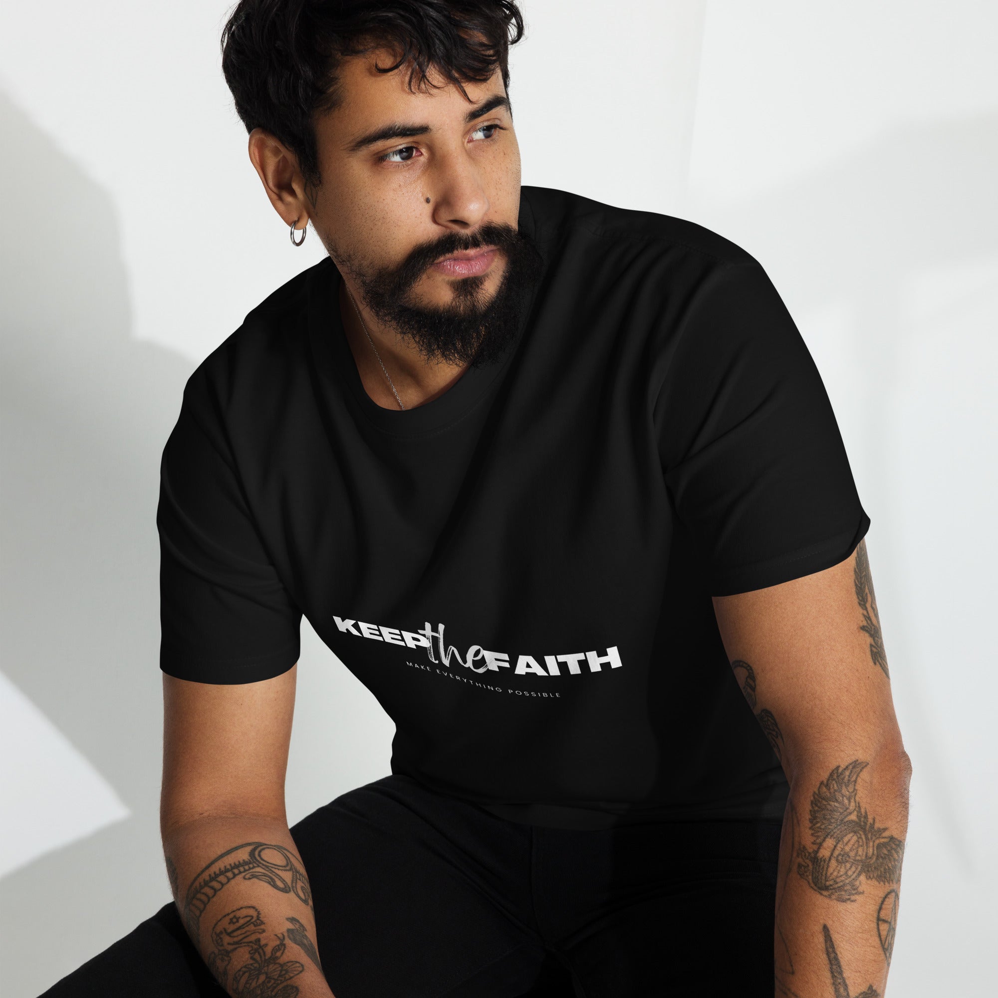 Man wearing black Keep The Faith t-shirt sitting indoors